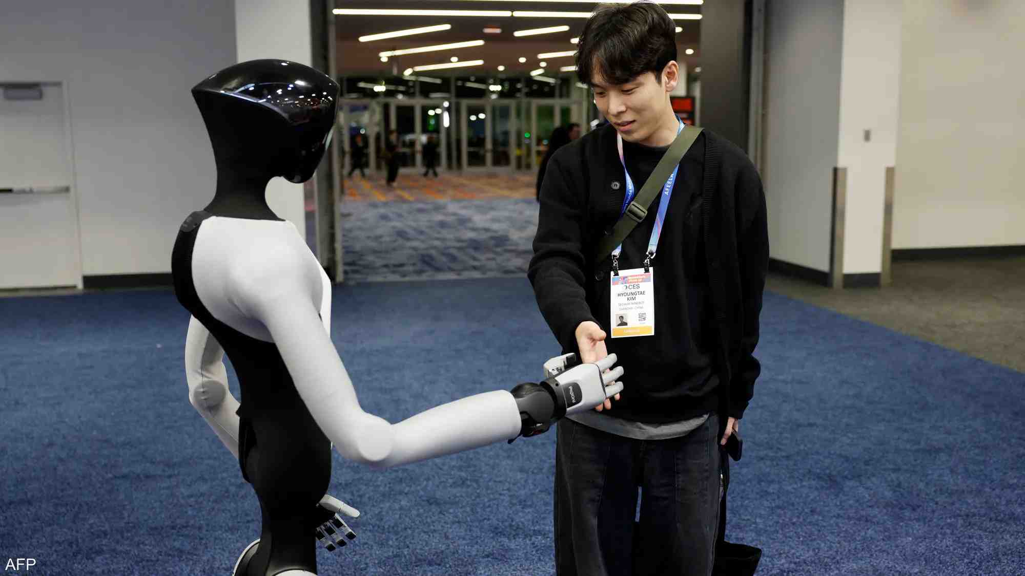A visitor shakes hands with a humanoid robot at CES