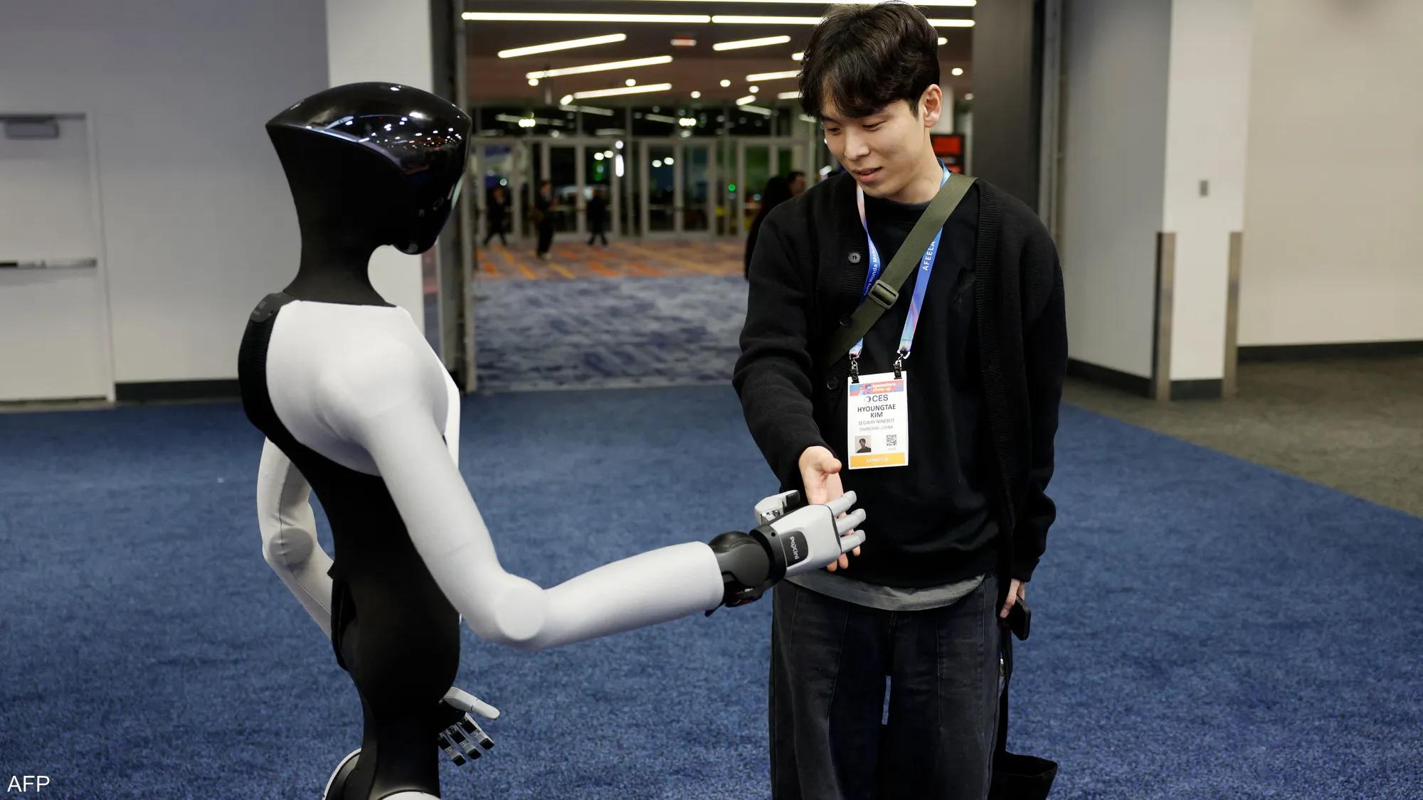 A visitor shakes hands with a humanoid robot at CES A visitor shakes hands with a humanoid robot at CES
