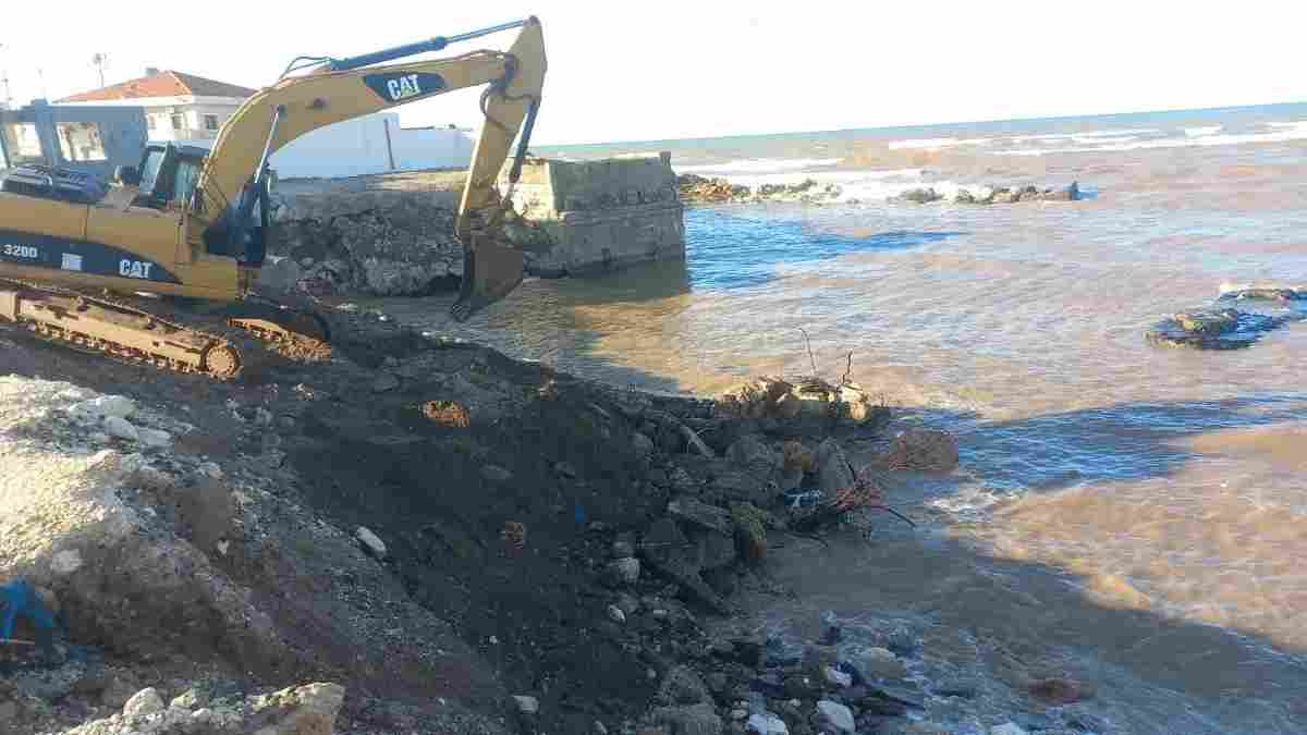 An excavator reinforces a crumbling coastline