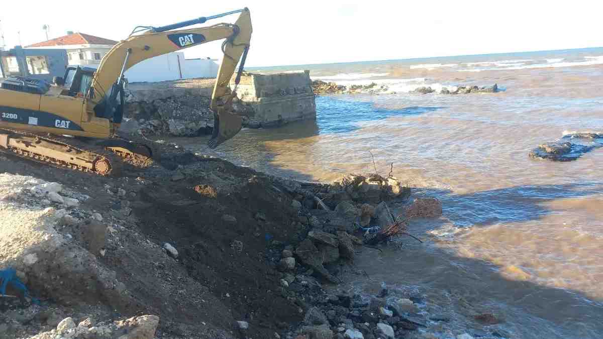 An excavator reinforces a crumbling coastline