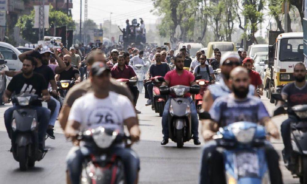 A large crowd of people on motorcycles fills a busy street A large crowd of people on motorcycles fills a busy street