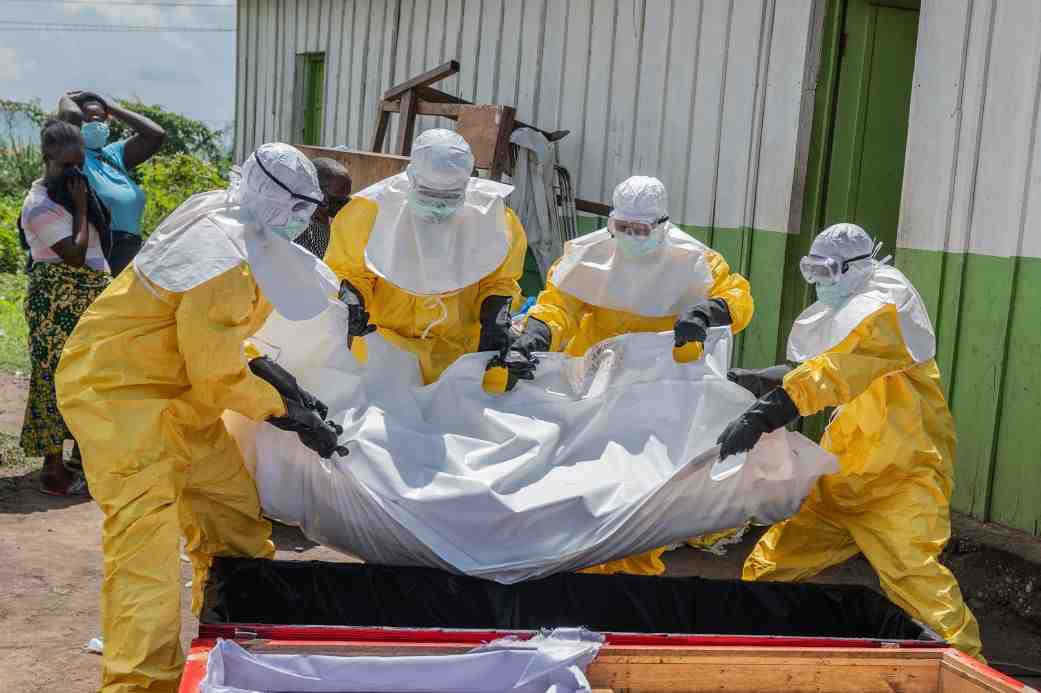 Red Cross workers carry the body of a person who died of Ebola into a coffin at a health center in Rwampara, Democratic Republic of Congo. (Image Credit: AP)