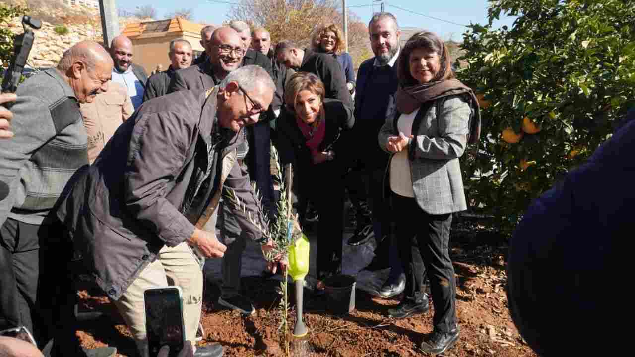 A group of officials and community members plant a young olive tree during an environmental restoration activity in southern Lebanon.