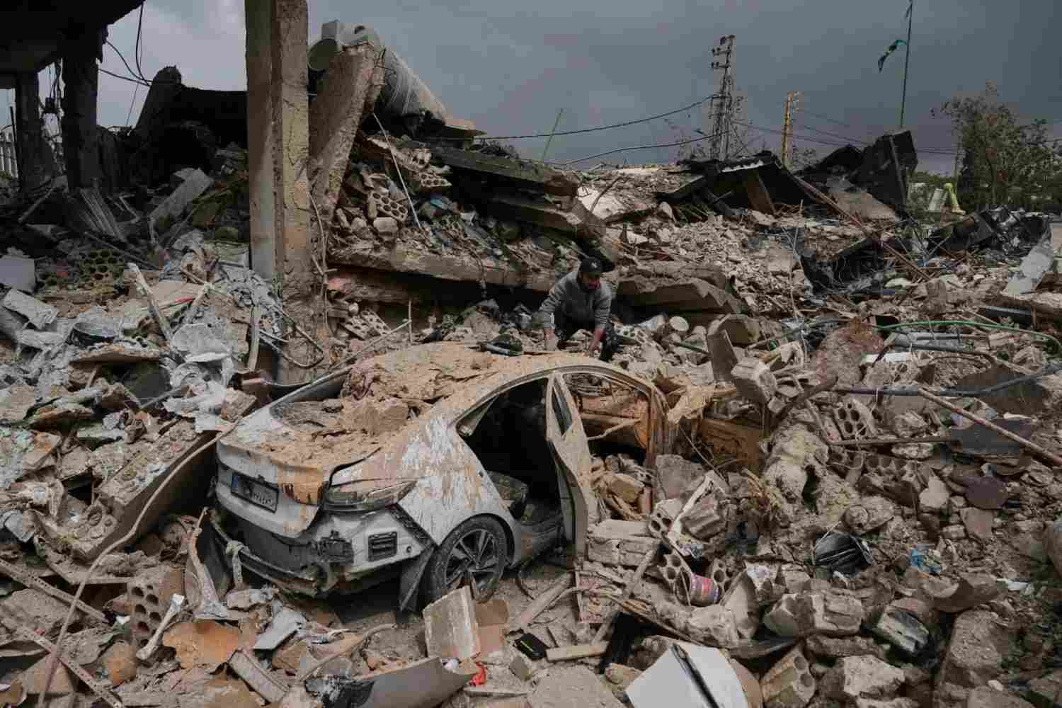 A man inspects his damaged car among the rubble of shops destroyed in previous Israeli airstrikes in the Hosh neighborhood of Tyre, southern Lebanon, April 19, 2026. (Image Credit: AP Photo/Bilal Hussein)