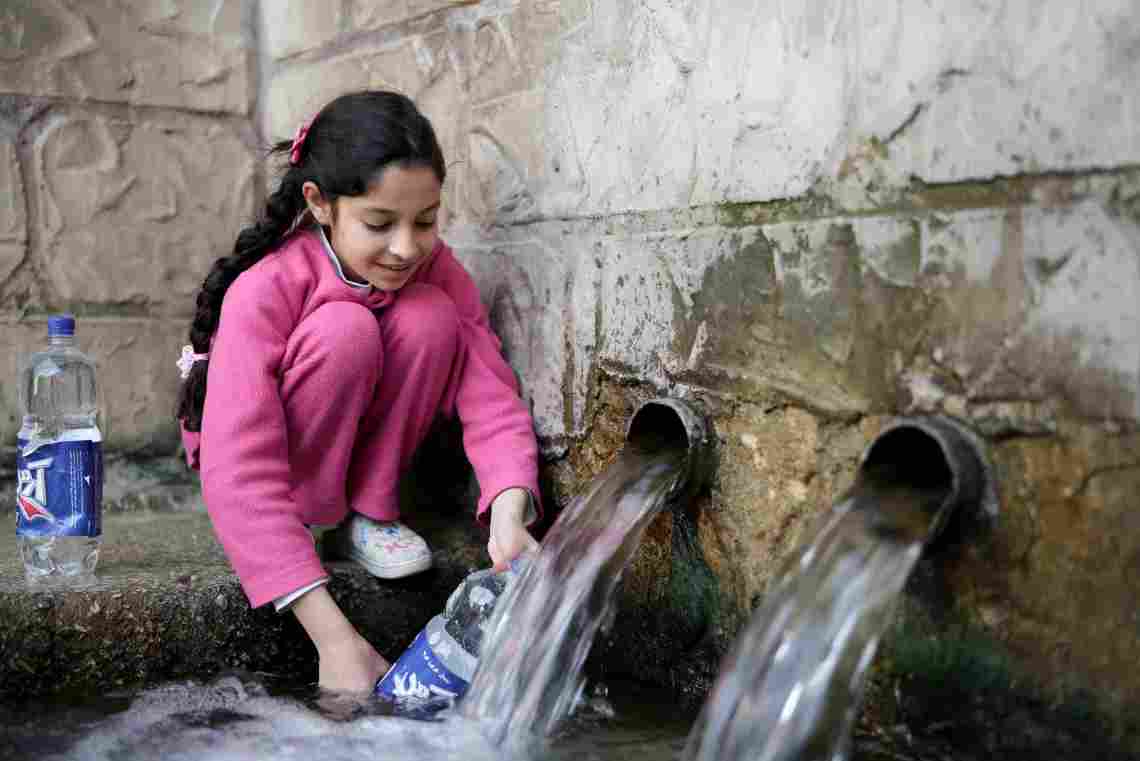 Young girl filling water bottles