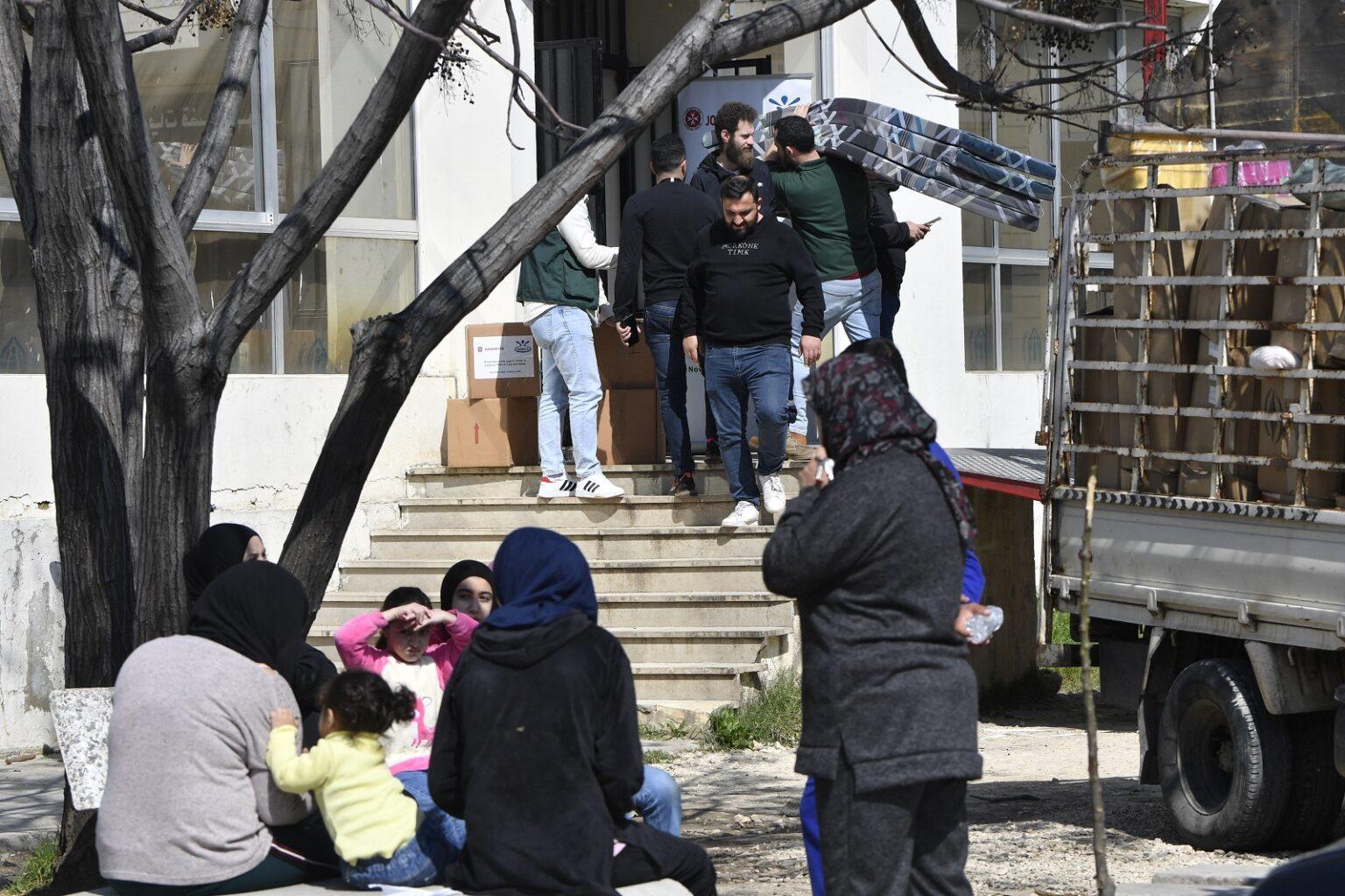 People are carrying beds inside a school People are carrying beds inside a school